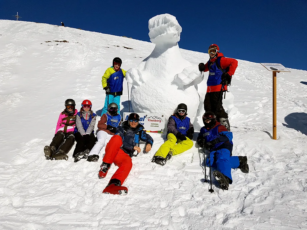 Gruppe posiert vor einer großen Schneeskulptur.